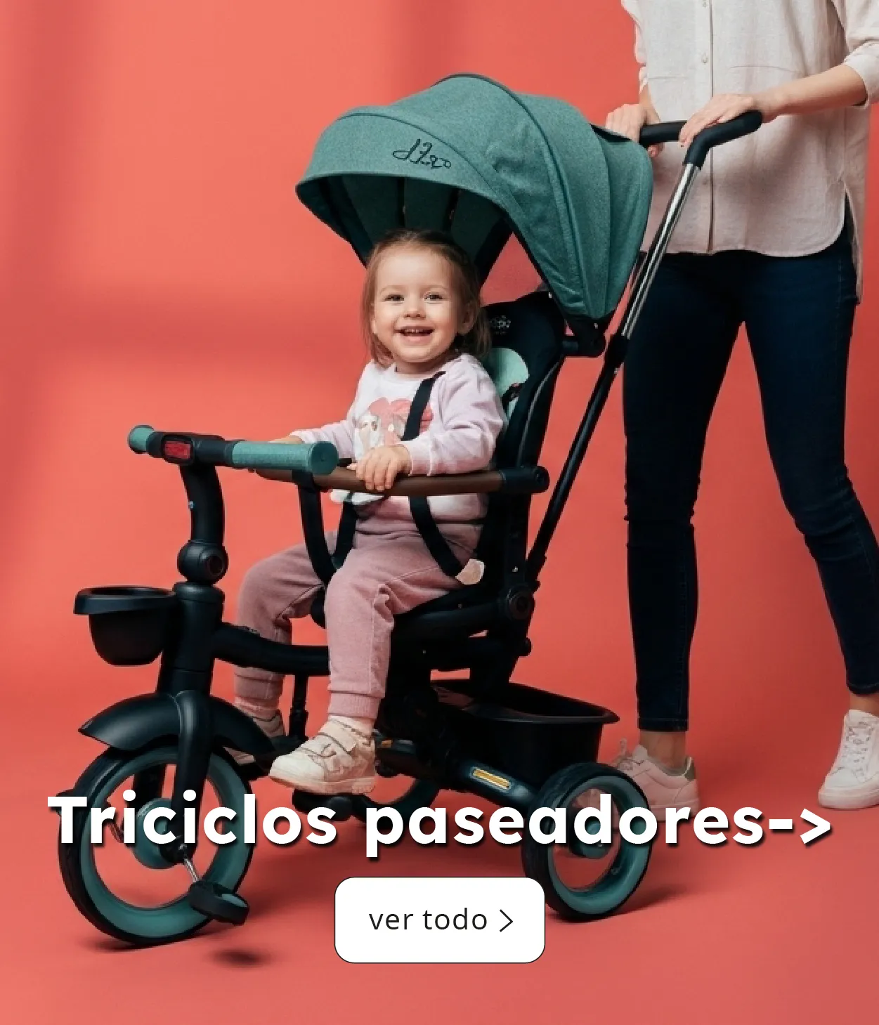 Bebé sonriendo en triciclo paseador verde con mango de empuje, acompañado por su madre